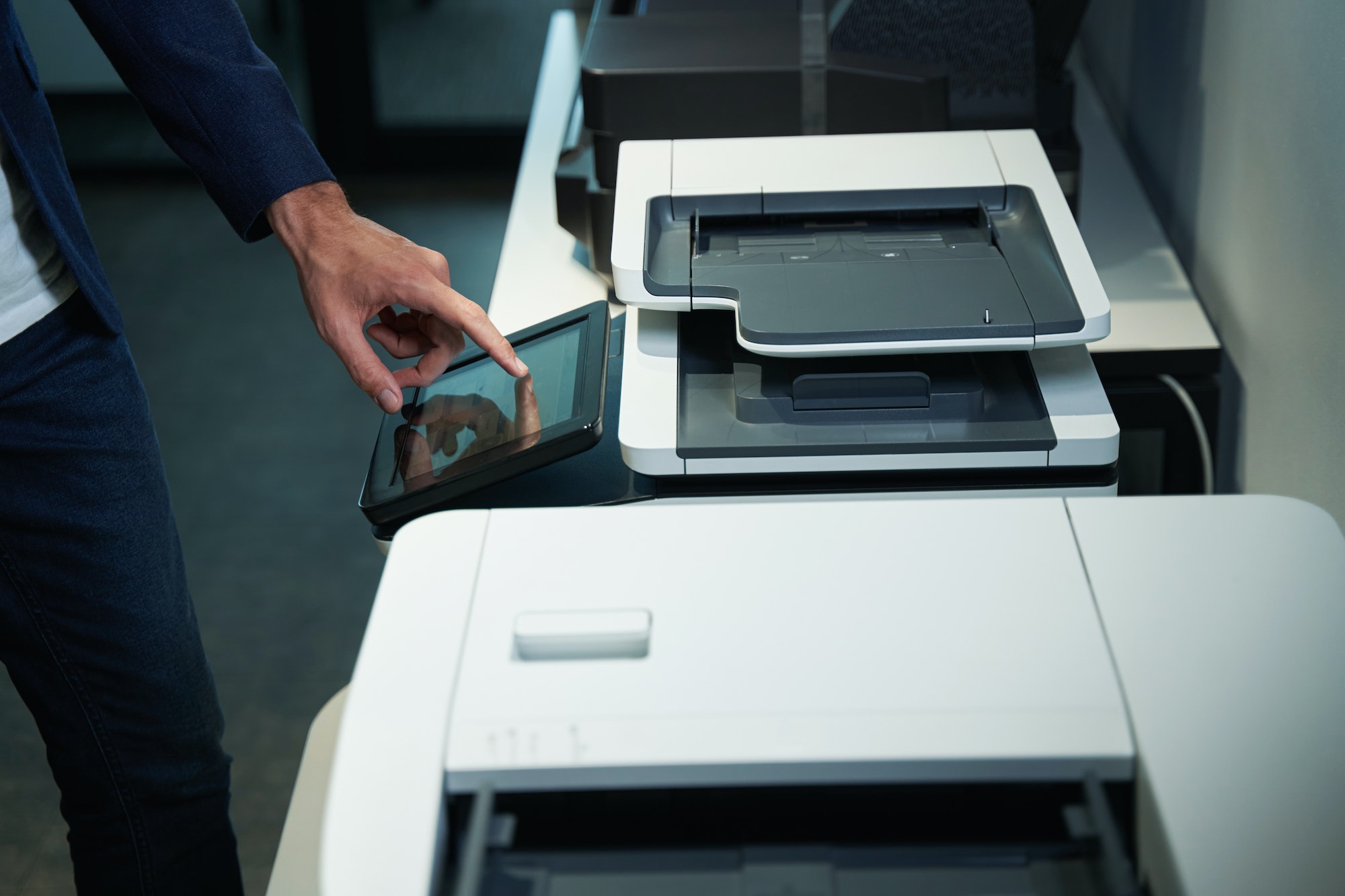 Person in office using printer and pressing on its screen